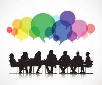 Individuals sitting around a table with different colors of speech bubbles arising to represent conversation.
